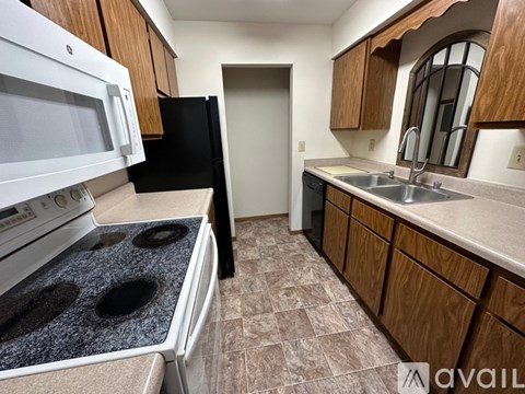 A kitchen with a white stove top oven and black refrigerator.