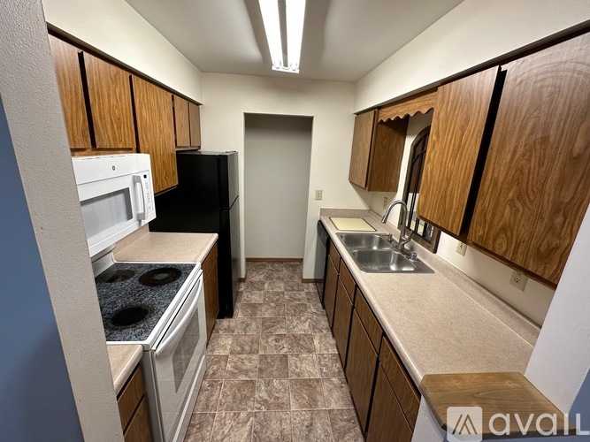 A kitchen with wooden cabinets and a black refrigerator.