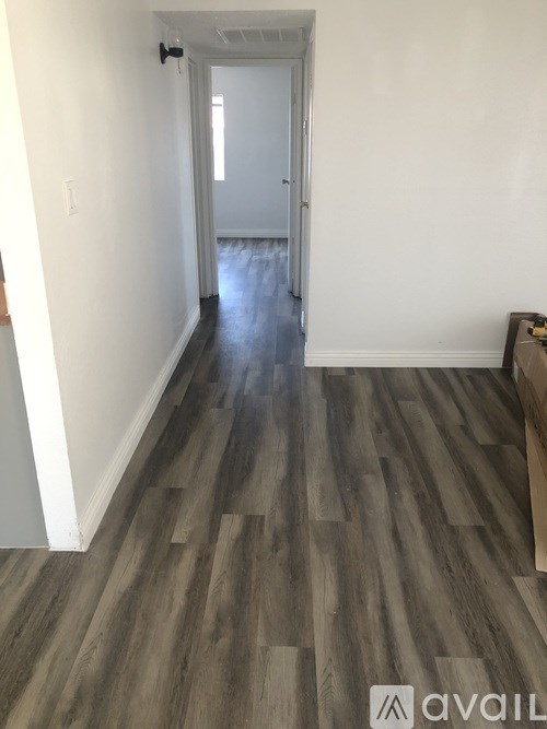 A hallway with wood flooring and a white door.