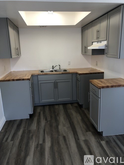 A kitchen with grey cabinets and a wooden countertop.