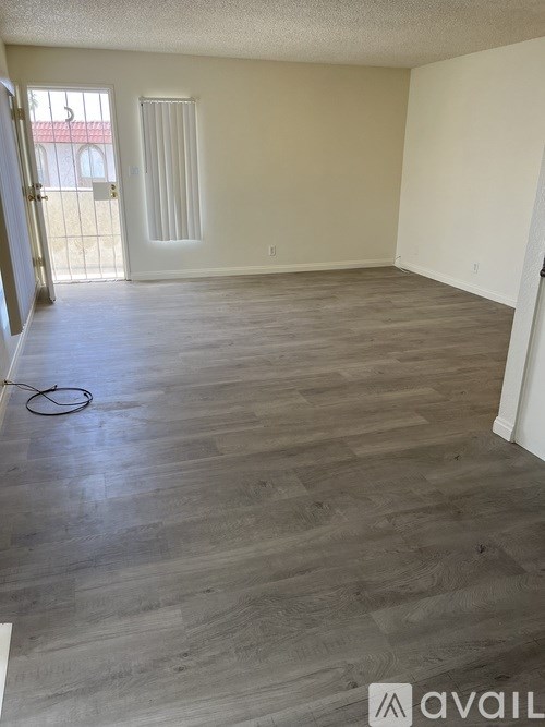 A room with wooden flooring and a door leading outside.