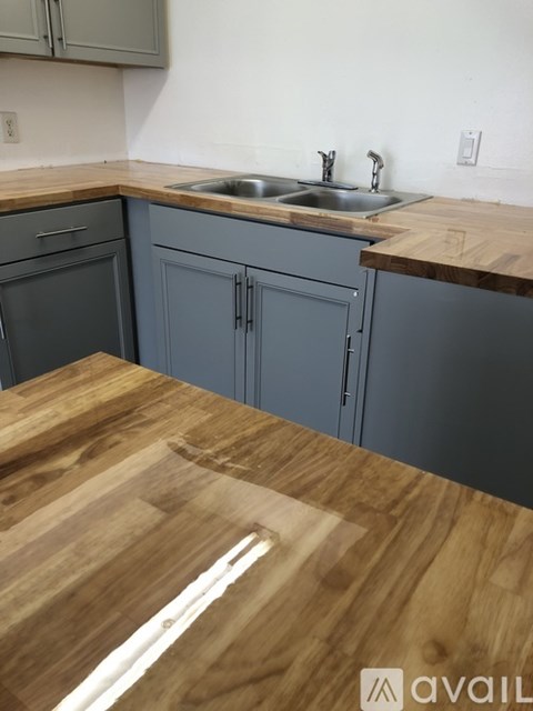 A kitchen with a wooden countertop and grey cabinets.