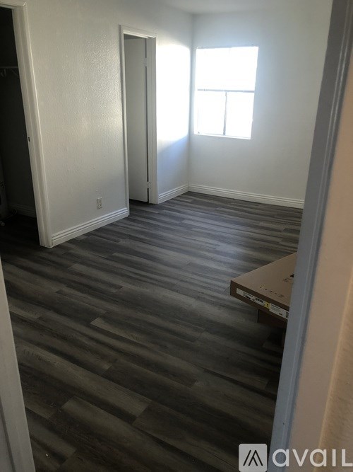 A room with a wooden floor and a window letting in sunlight.