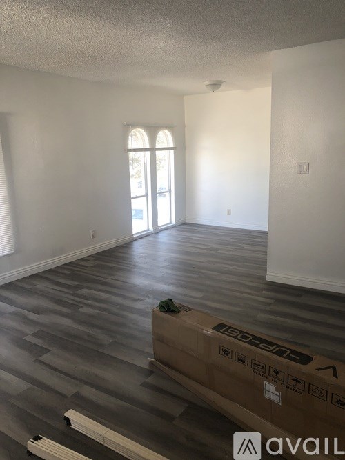 A room with a box on the floor and a window with blinds.