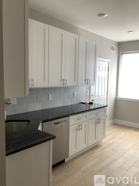 A kitchen with white cabinets and a black countertop.