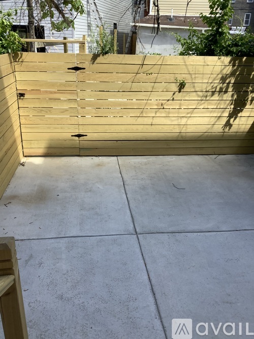 A wooden fence with a concrete floor in front of it.
