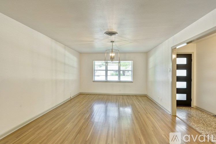 A room with wooden floors and a window with a hanging light fixture.