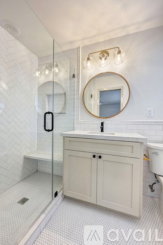 A bathroom with a white tiled shower and a white sink vanity.