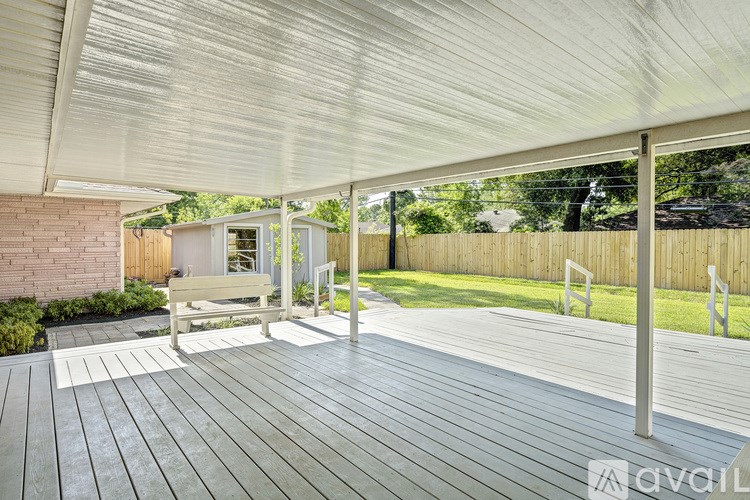 A wooden deck with a white canopy and a bench.