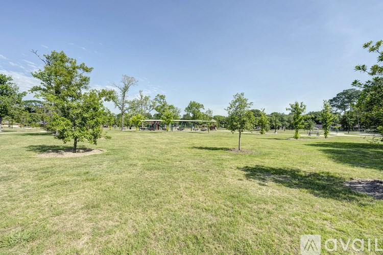 A grassy field with trees and a clear sky.
