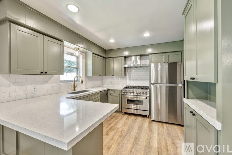 A modern kitchen with a white countertop and stainless steel appliances.