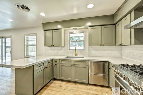 A kitchen with a stainless steel dishwasher and a window.