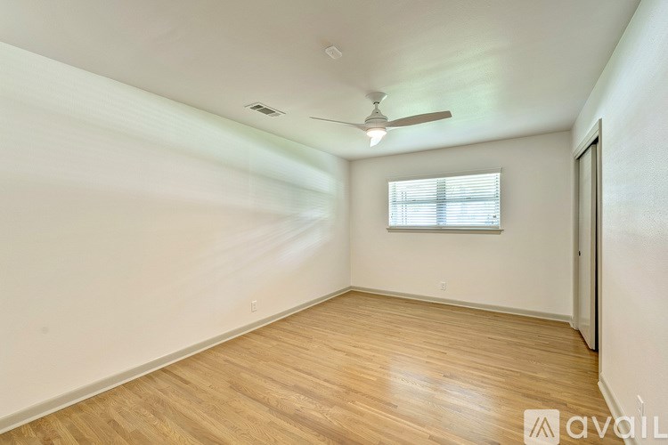 A room with wooden flooring and a window with blinds.