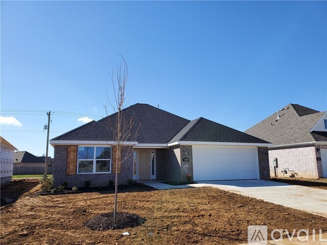 A single-story house with a garage and a small tree in front.
