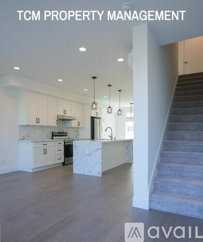 A modern kitchen with white cabinets and a marble island.