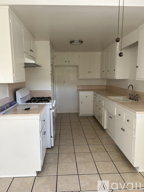 A kitchen with white cabinets and a tiled floor.