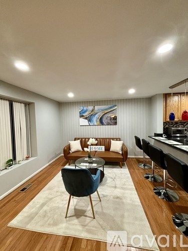A living room with a blue chair in the center and a painting on the wall.
