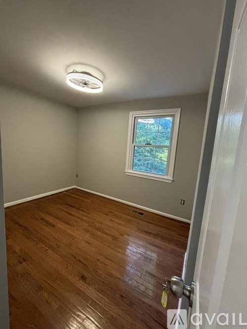 A room with a window and wooden flooring.