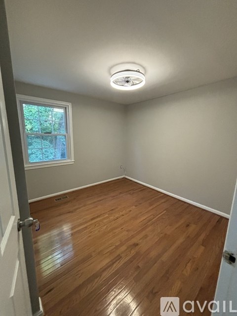 A room with wooden flooring and a smoke detector on the ceiling.