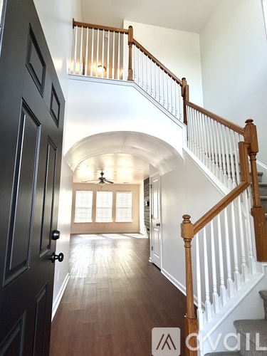 A wooden staircase with white railings leads to a living room.