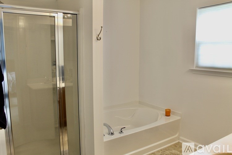 A bathroom with a glass shower door and a white bathtub.