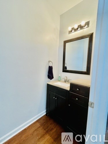 A bathroom with a sink, mirror, and cabinet.