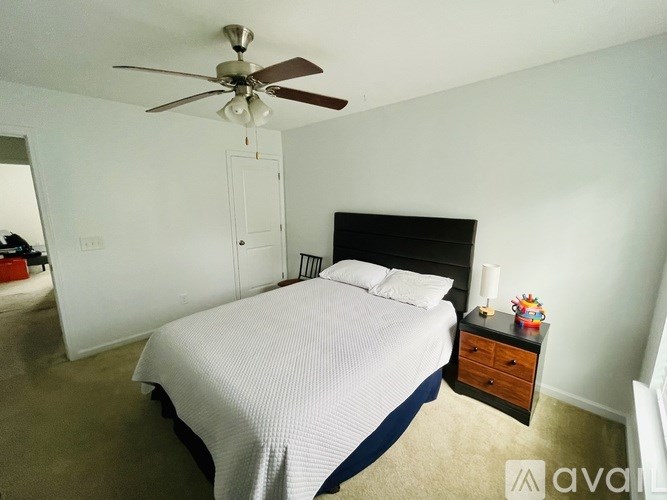 A bedroom with a bed, dresser, and ceiling fan.