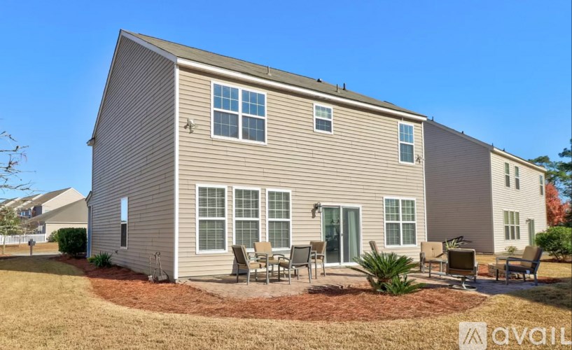 A house with a grey siding and a brown roof with a patio in front.