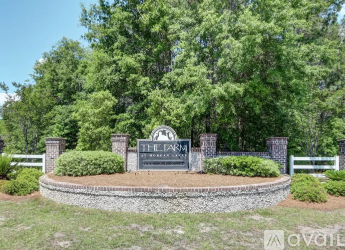 A sign that says "The Farm" is in front of a fence and trees.