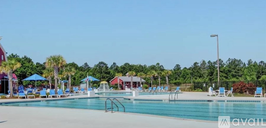 A large outdoor swimming pool surrounded by trees and lounge chairs.