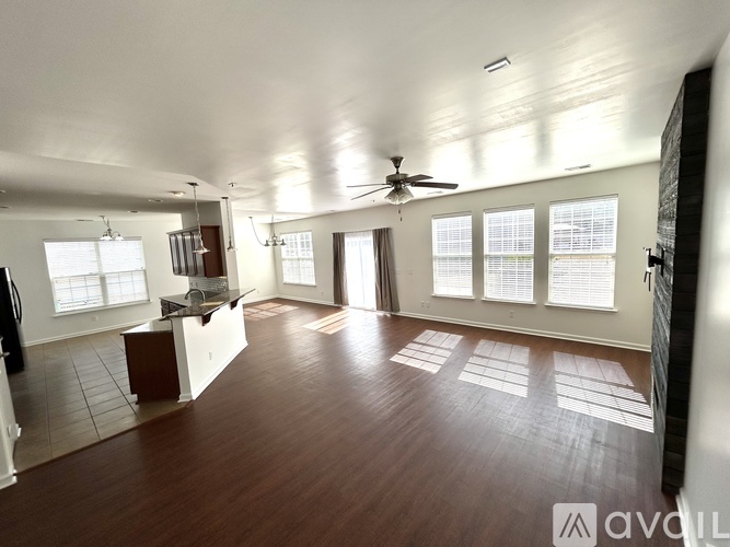 A spacious room with wooden floors and a ceiling fan.