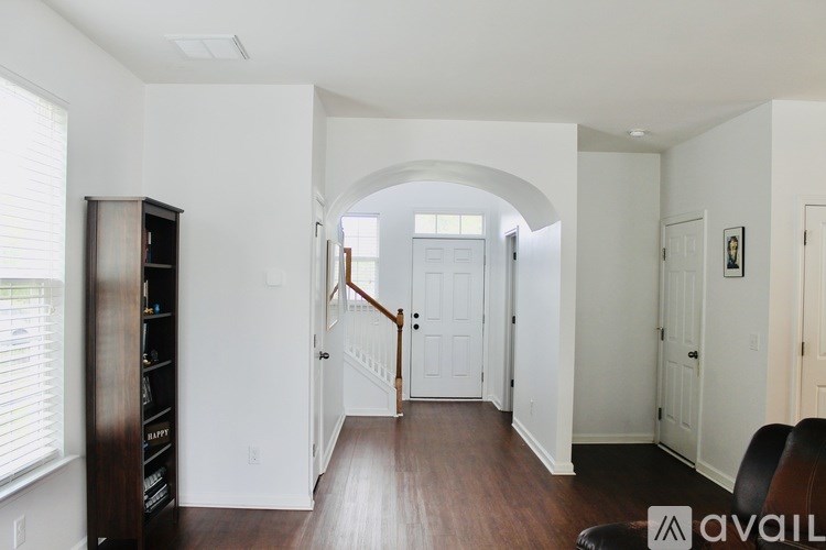 A living room with a white archway and a brown floor.