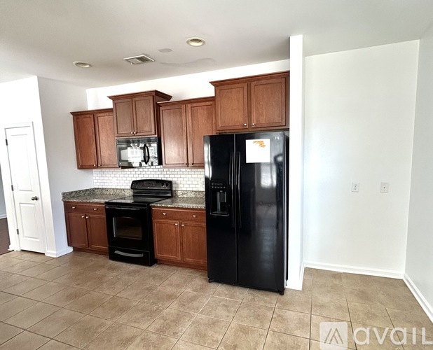 A kitchen with brown cabinets and a black refrigerator.