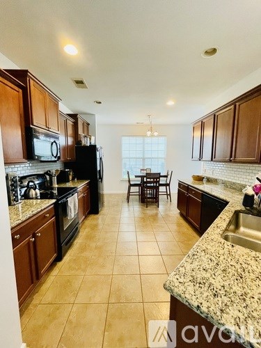 A kitchen with brown cabinets and a black refrigerator.
