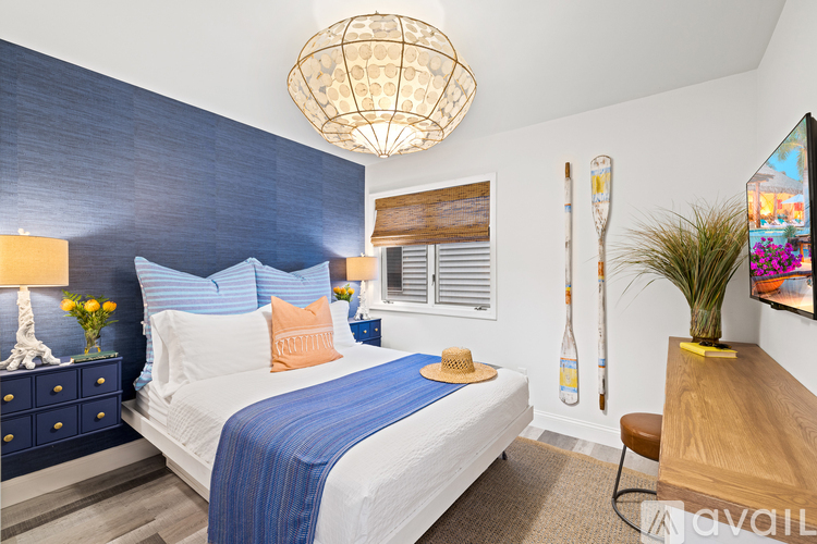 A bedroom with a bed, a chair, a dresser, and a painting on the wall.