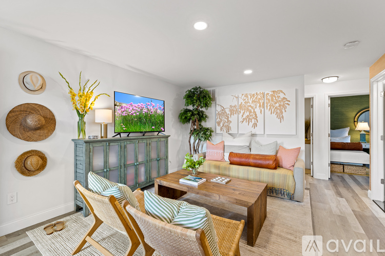 A living room with a sofa, a chair, a coffee table, and a flat-screen TV mounted on the wall.