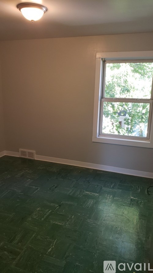 A room with a window and a green floor.