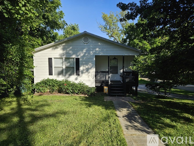 A small white house with a black porch.