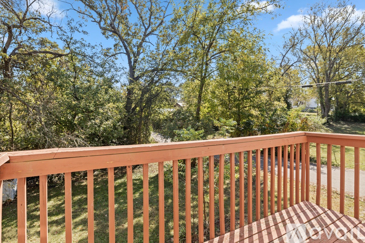 A wooden deck with a railing overlooking a grassy area with trees.