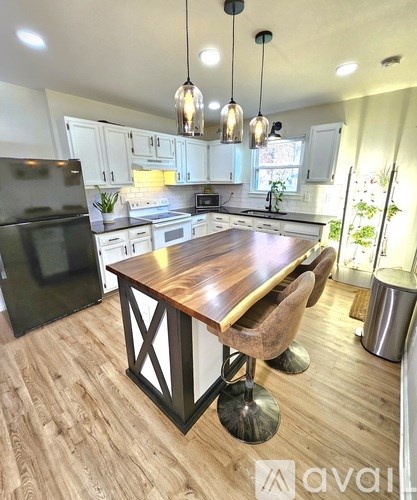 A kitchen with a wooden table and black fridge.