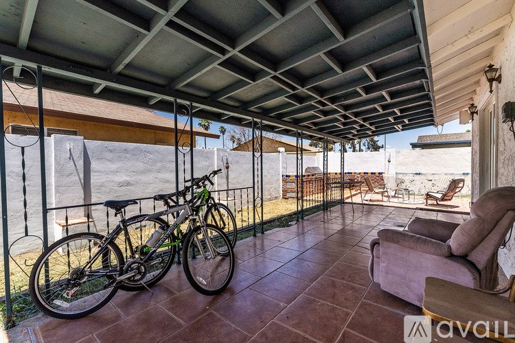 A bicycle is parked on a patio with a couch and chairs.
