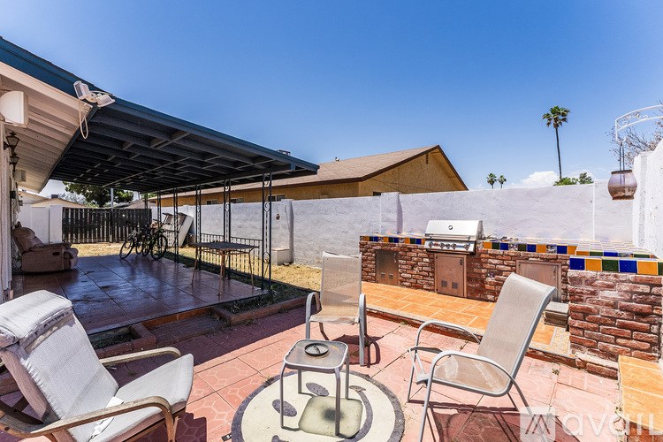 A patio with a table and chairs under a roof.