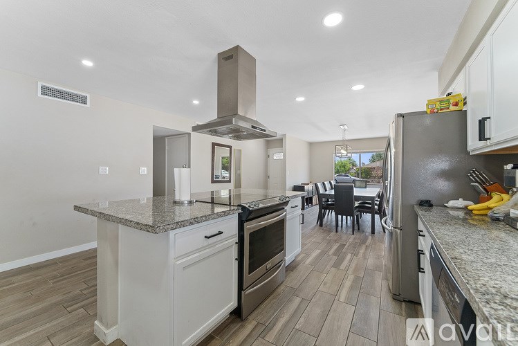 A modern kitchen with a dining table and chairs in the background.