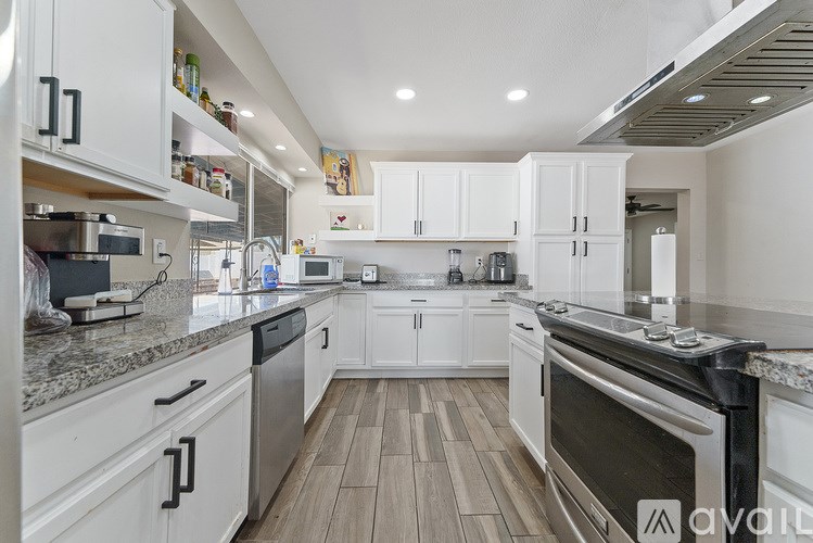 A kitchen with white cabinets and a wooden floor.