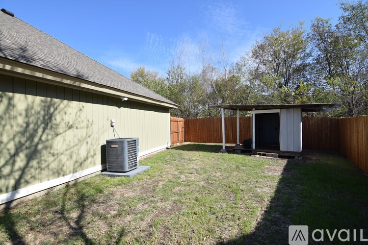 A backyard with a fence, a shed, and a wall-mounted air conditioning unit.