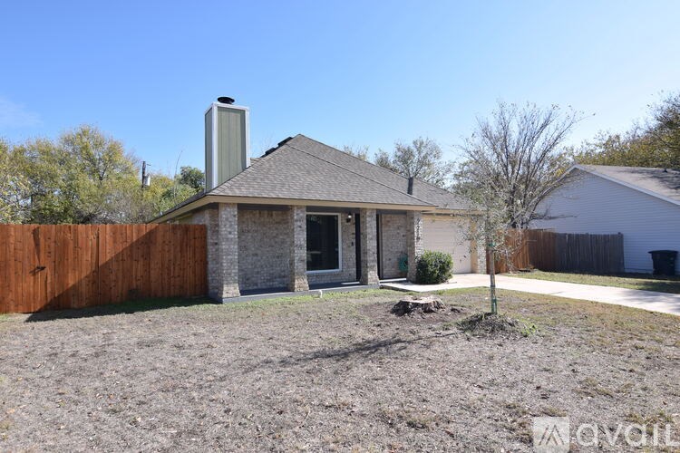 A house with a brown fence and a tree in front of it.