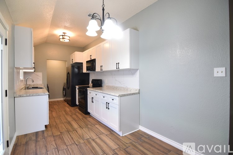 A kitchen with white cabinets and a black fridge.