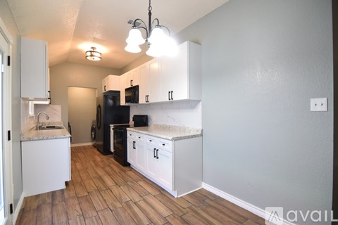 A kitchen with white cabinets and a black fridge.