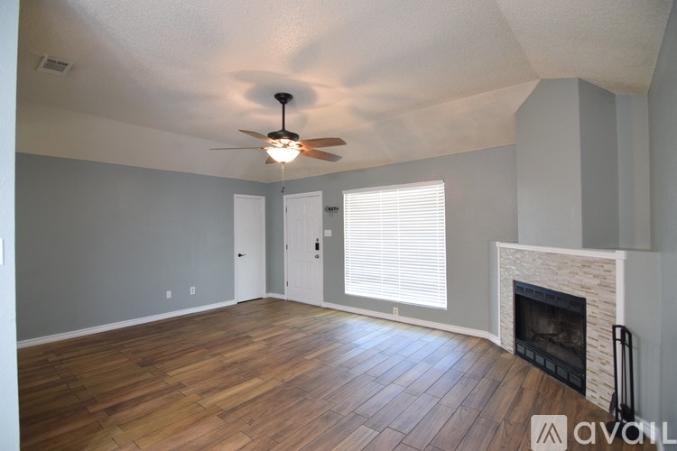 A living room with a fireplace and a ceiling fan.