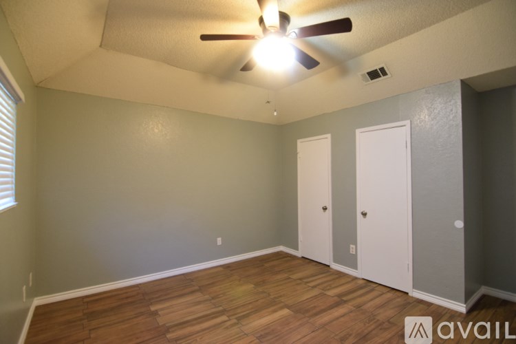 A room with a ceiling fan and a window with blinds.